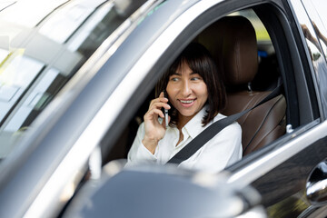 Portrait of a beautiful woman sitting in car as a driver and talking phone. Concept of business transfer services, chauffeur portrait or business trips