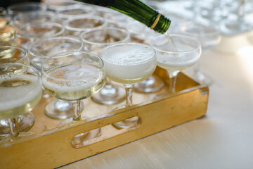 Close up of champagne being poured into modern glasses from champagne bottle