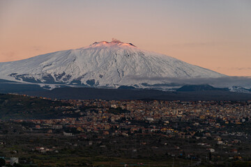 Bronte town under the snowy and majestic volcano Etna and a cloudy blue sky