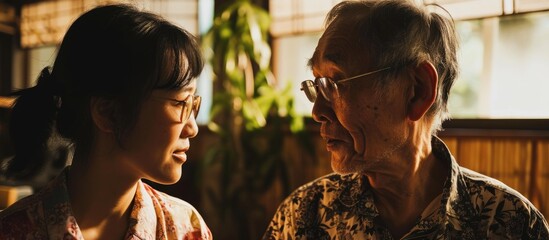 Asian daughter and elderly father enjoying quality time and conversation at home. - obrazy, fototapety, plakaty
