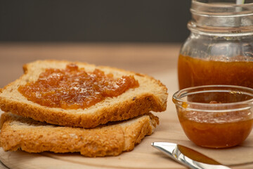 Mandarin jam on wooden plate with knife and bread. Made in Sicily