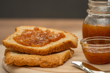 Mandarin jam on wooden plate with knife and bread. Made in Sicily
