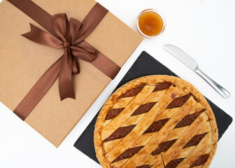 Round shortcrust tart and mandarin jam on a white background with a gift package. Made in Sicily