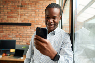 Happy young businessman using smartphone at office