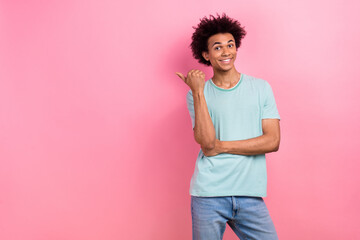 Photo of confident positive guy wear blue t-shirt showing thumb empty space isolated pink color background