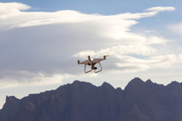 Fototapeta na wymiar A quadcopter hovering in the cloudy sky shooting & broadcasting a live video 