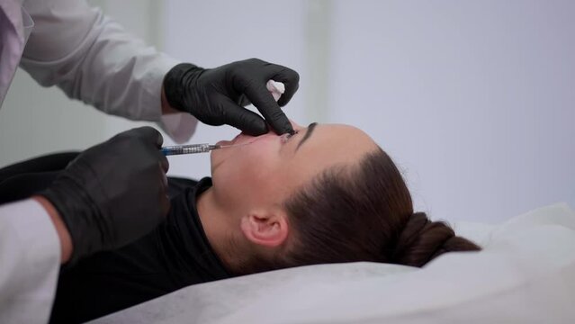 The doctor injects Botox into the face with a syringe