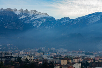 Beautiful landscape of the layered misty hazy Italian Alps mountain range during evening. Alpine summer sunrise. Lombardy, Italy