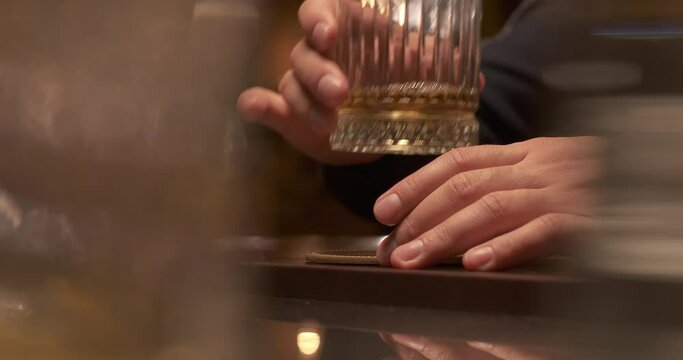 Man resting with glass of whiskey at hotel lounge. Spending time in restaurant with expensive alcohol. Close-up glass of whiskey. Selective focus