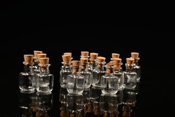 Glass bottles with cork on a black mirror surface with reflections isolated on black background