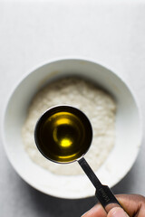 olive oil in a measuring spoon, measuring a tablespoon of oil