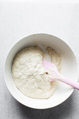Focaccia dough in a white bowl, process of making focaccia, dough rising in a white mixing bowl