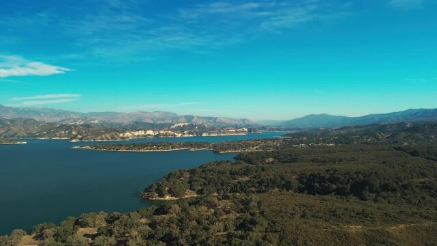 Aerial wide shot over water reservoir and a large dam that holds water in California, USA