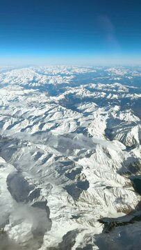 Stunning view across the European Alps in winter. Snowy mountain peaks under bright blue sky.