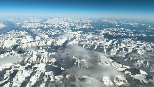 Stunning view across the European Alps in winter. Snowy mountain peaks under bright blue sky.
