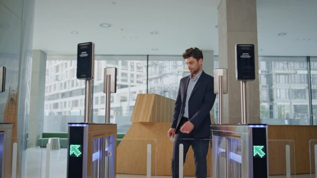 Man entering office automatic gates using electronic card reader at building.