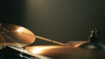 Rock musician drummer plays drums in a dark studio. Female drummer hits drum plates. Close-up