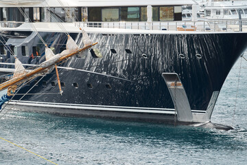 Sun glare on glossy board of mega yacht, anchor, tranquillity in port Hercules, bow of moored huge...