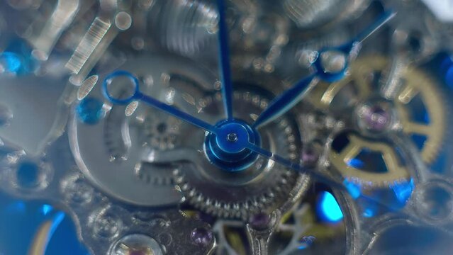Beautiful internal structure of a skeleton wristwatch where shiny gears, wheels and hands move with sparkling bokeh. Closeup. Macro. Shallow depth of field