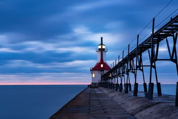 Fotobehang lighthouse on the pier at sunset © Andrew
