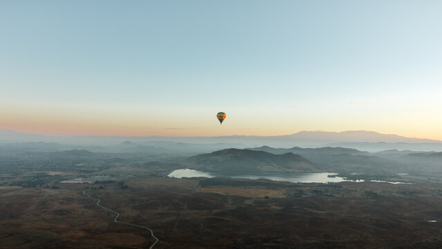 The Lone Balloon: Floating silently at sunrise above the Temecula Valley Wine Country with Skinner Reservoir in the background.