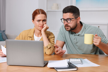 Emotional couple doing taxes at table in room