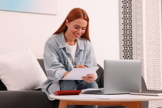 Woman calculating taxes at table in living room