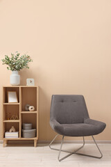 Living room interior with comfortable armchair and shelving unit near beige wall indoors