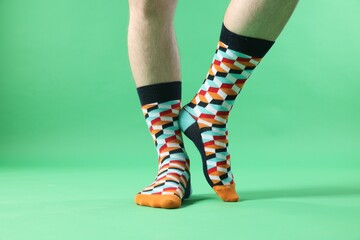 Man in stylish colorful socks on light green background, closeup