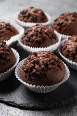 Tasty chocolate muffins on grey textured table, closeup