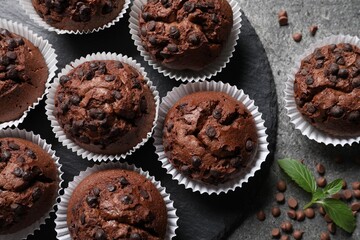 Tasty chocolate muffins on grey textured table, flat lay