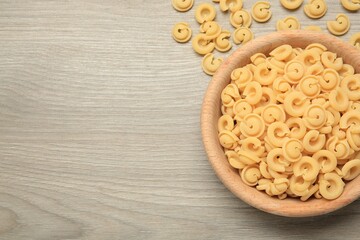 Raw dischi volanti pasta in bowl on light grey wooden table, top view. Space for text