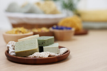 Tray with soap bars on light wooden table, space for text. Spa therapy