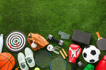 Different sport equipment and sneakers on green grass, flat lay. Space for text