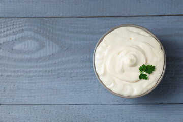 Tasty mayonnaise and parsley in bowl on gray wooden table, top view. Space for text