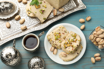 Tasty halva with pistachios served on light blue wooden table, flat lay