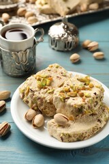 Tasty halva with pistachios served on light blue wooden table