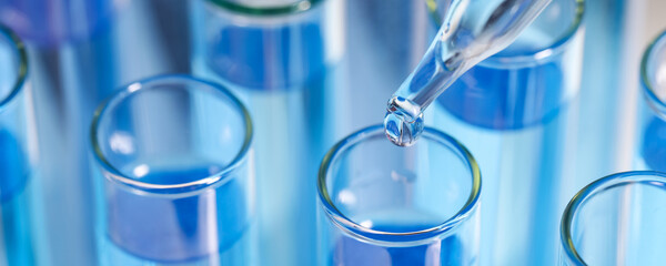 Laboratory analysis. Dripping reagent into test tube, closeup. Banner design