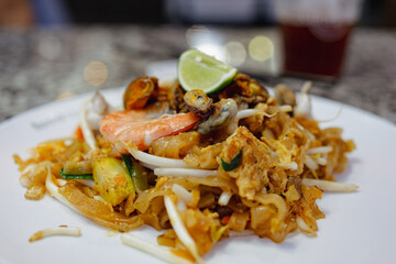 Pat Thai, rice noodles fried with tofu, vegetable, egg and seafood on plate in Thailand