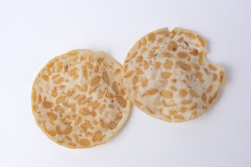 Keripik Tempe or Tempeh Chips are made from soybeans and served on a wooden plate. Isolated on white background. usually used as souvenirs