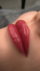 permanent makeup on the lips of a young woman of a delicate peach shade close-up, a girl after a...