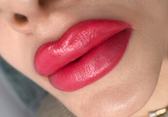 permanent makeup on the lips of a young woman of a delicate peach shade close-up, a girl after a cosmetic procedure with smooth and clean healthy skin.