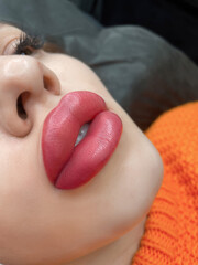 permanent makeup on the lips of a young woman of a delicate peach shade close-up, a girl after a...