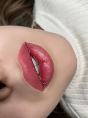 Fototapeta premium permanent makeup on the lips of a young woman of a delicate peach shade close-up, a girl after a cosmetic procedure with smooth and clean healthy skin.