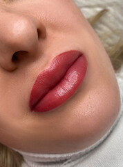 permanent makeup on the lips of a young woman of a delicate peach shade close-up, a girl after a...