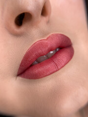 permanent makeup on the lips of a young woman of a delicate peach shade close-up, a girl after a cosmetic procedure with smooth and clean healthy skin.