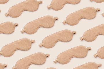 Trendy Minimal pattern from beige sleep masks on beige background, above view. Neutral colored stylish cloth eye masks for best sleeper, for travel, rest. Night time and sleep concept