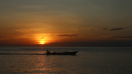 Naklejka na ściany i meble Silhouette of a Boat on the Sea at Sunset
