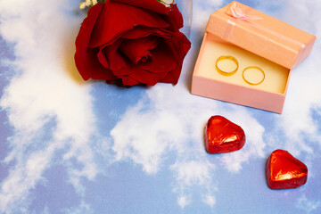 valentines day rose chocolates and rings in a box on a sky background pattern
