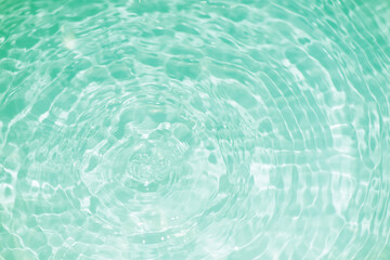 Green water waves on the surface ripples blur. Defocus blurred transparent blue colored clear calm water surface texture with splash and bubbles. Water waves with shining pattern texture background.